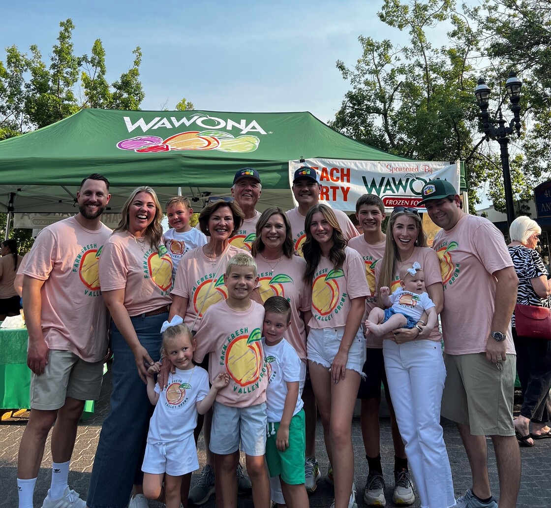 Family enjoying Wawona Frozen Foods at a vibrant community festival under sunny skies.