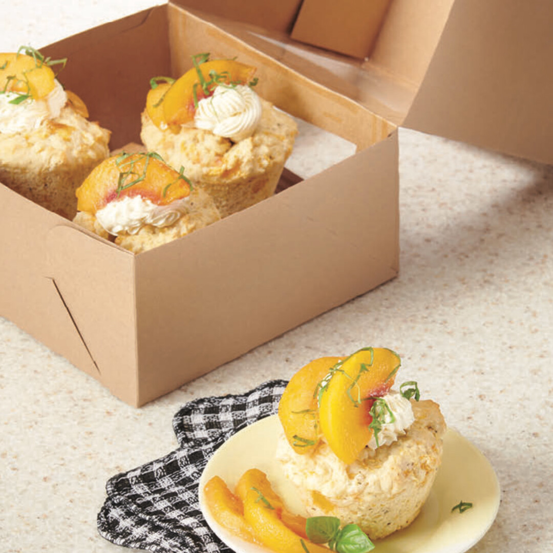 Delicious peach cupcakes topped with cream and mint, perfect for desserts and gatherings.