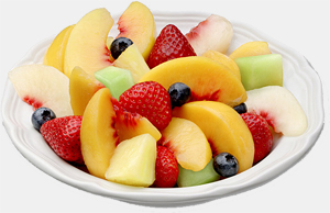 Colorful fruit salad in an elegant porcelain bowl, featuring peaches, melons, strawberries, and blueberries.