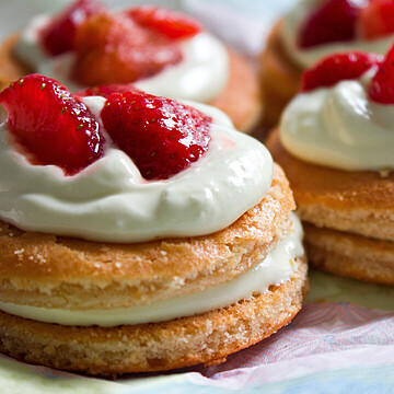 Delicious layered strawberry cakes with fluffy cake, creamy frosting, and fresh strawberries on top.