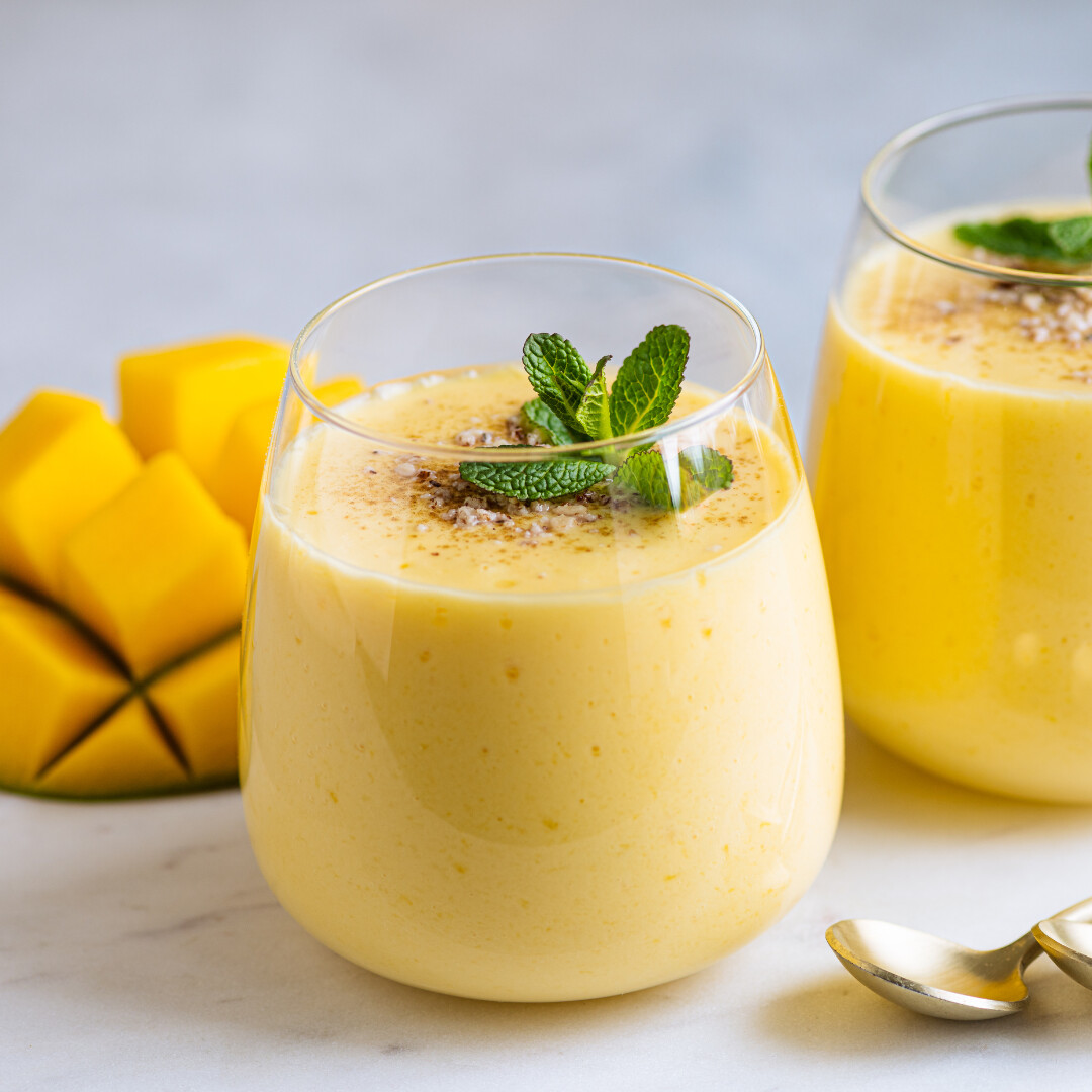 Delicious mango smoothie topped with mint, served fresh with ripe mango chunks.