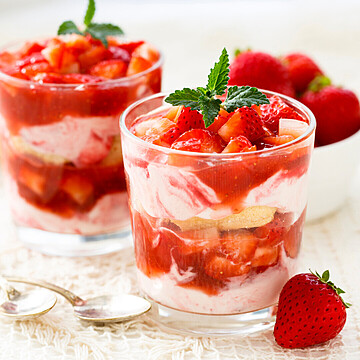 Delicious strawberry parfait dessert with layers of strawberries, cream, and sponge cake in elegant glasses.