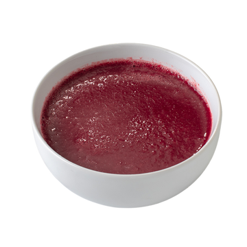 Vibrant red soup in a smooth white bowl against a black background.