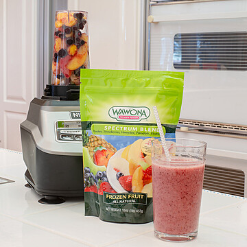 High-performance blender with Wawona frozen fruits making a vibrant smoothie in a modern kitchen.