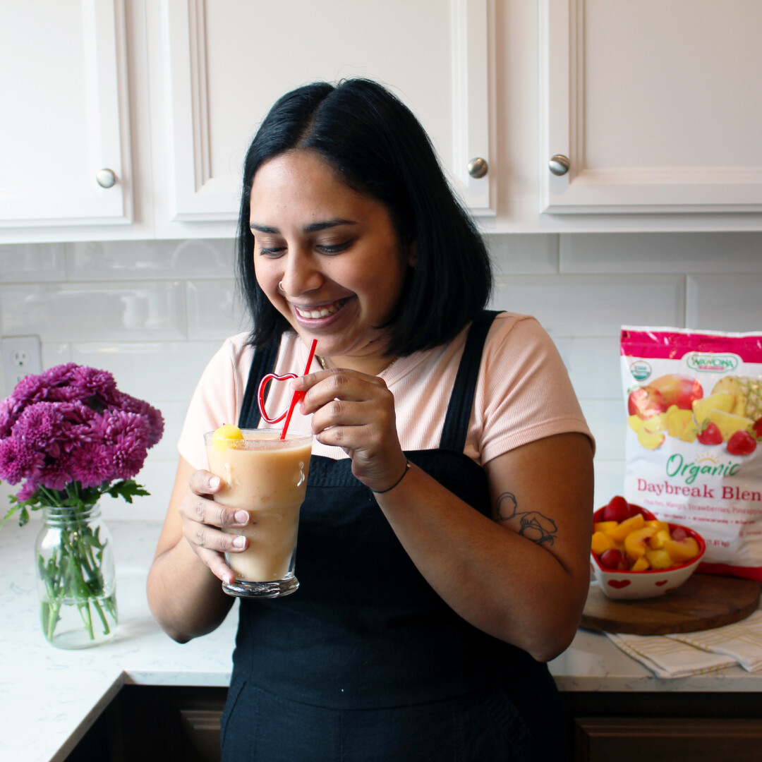 Woman enjoying a refreshing peach smoothie in a bright, modern kitchen.